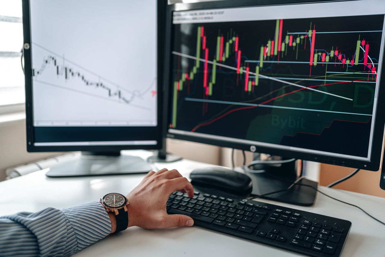 Crafting Captivating Headlines: Your awesome post title goes here A businessperson using dual monitors to analyze stock market trends with charts and graphs.